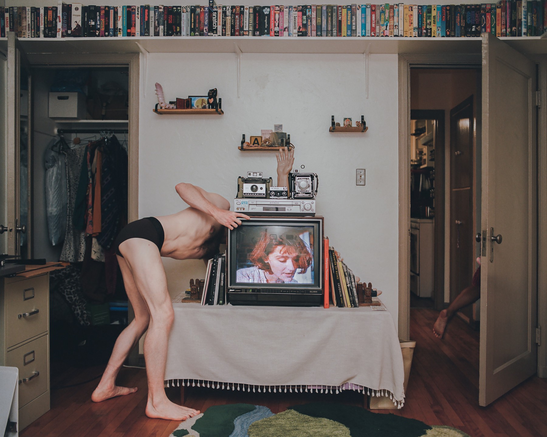 A man bending behind a television in a family room