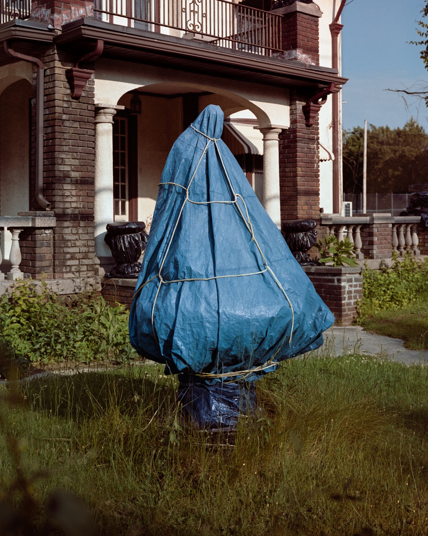 An object wrapped in blue fabric outside a house