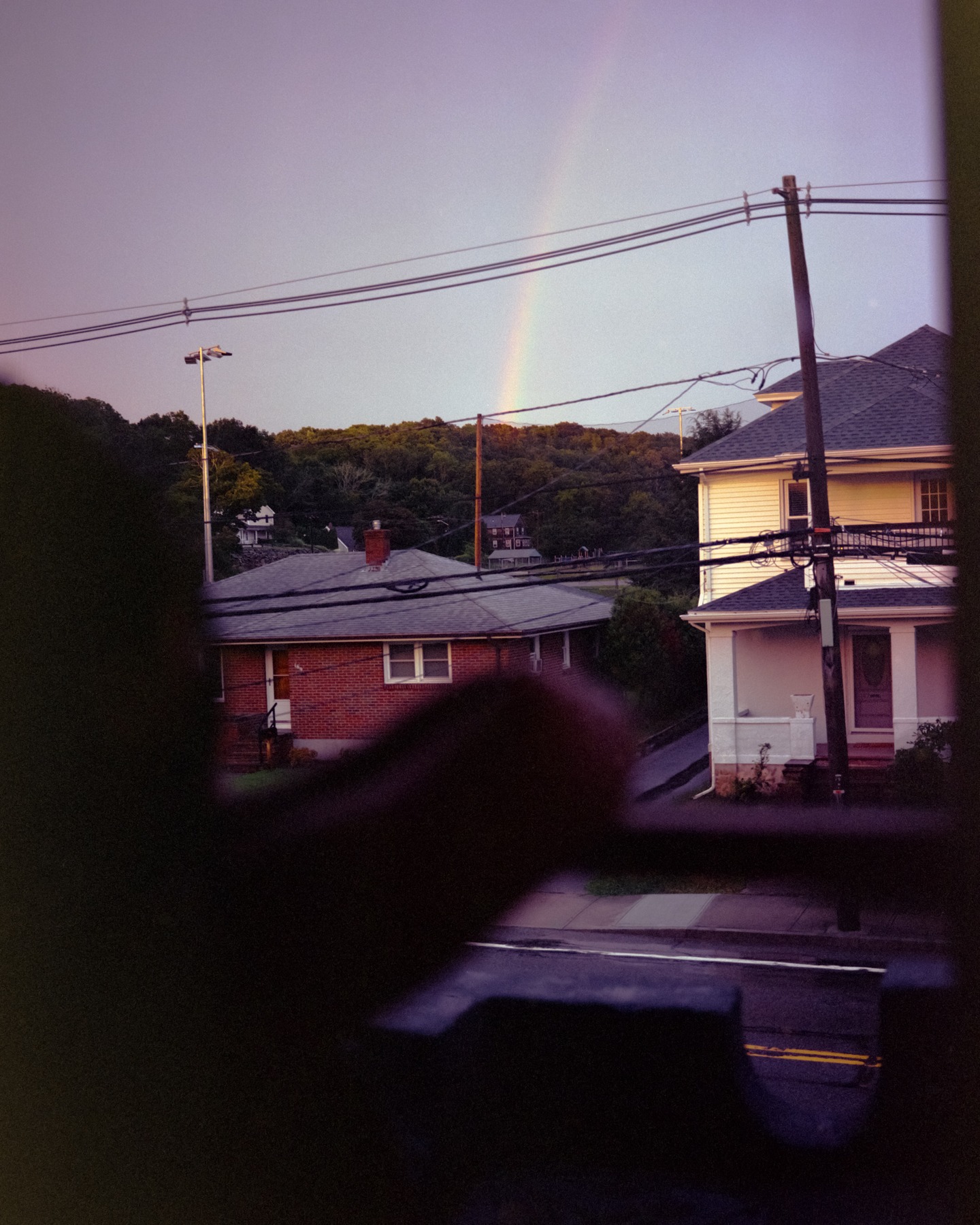 A rainbow over houses and utility lines