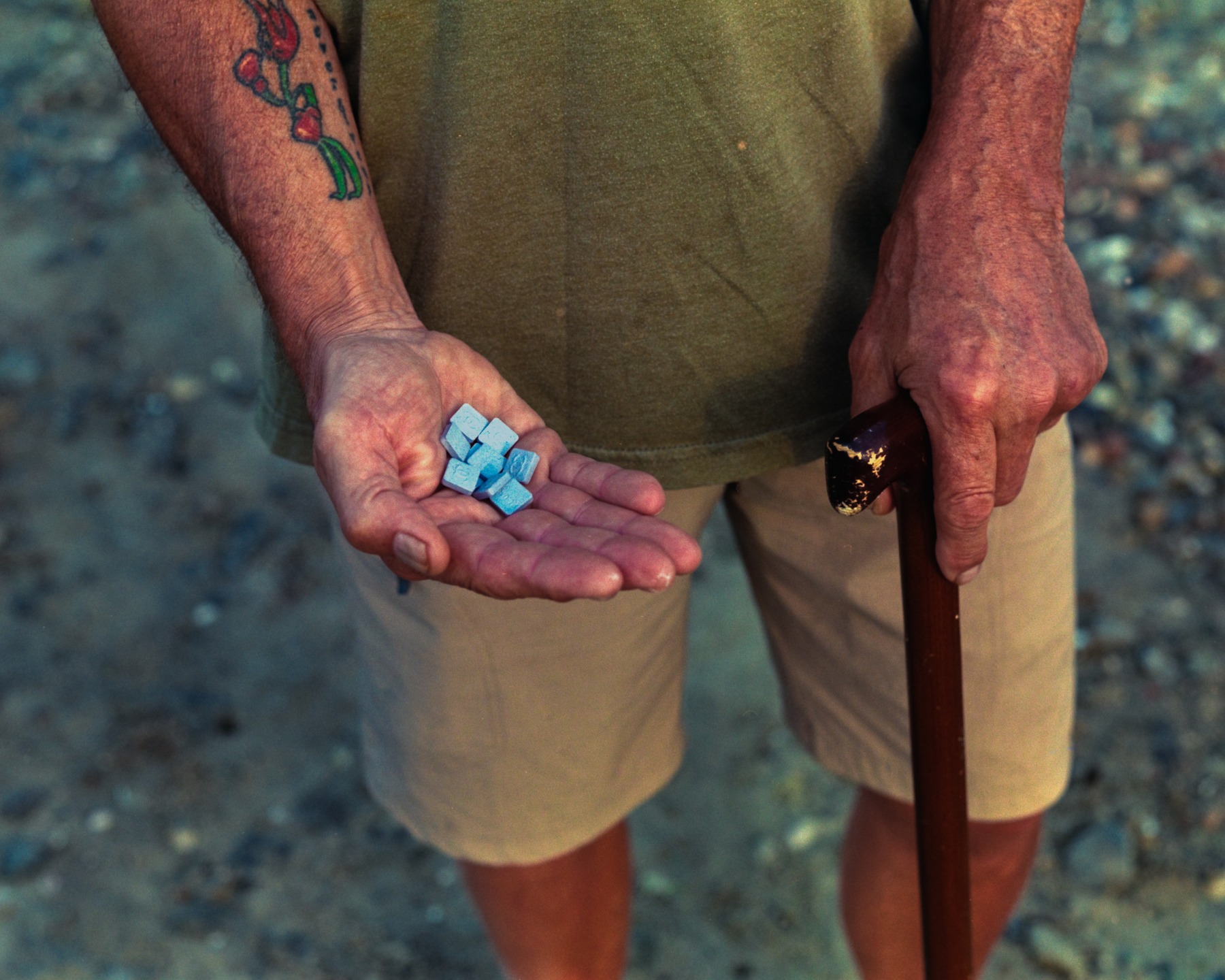 A tattooed man holding small colored objects in his palm