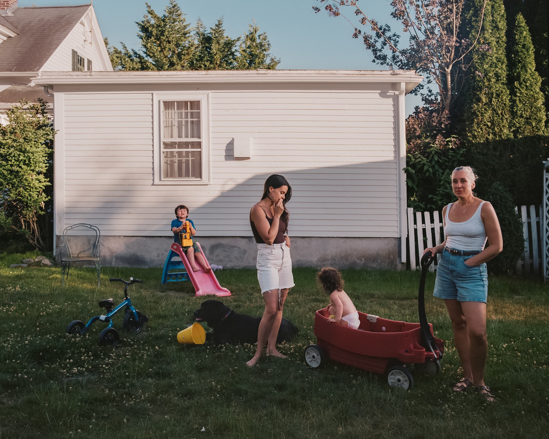 A family gathered in a backyard beside a small slide