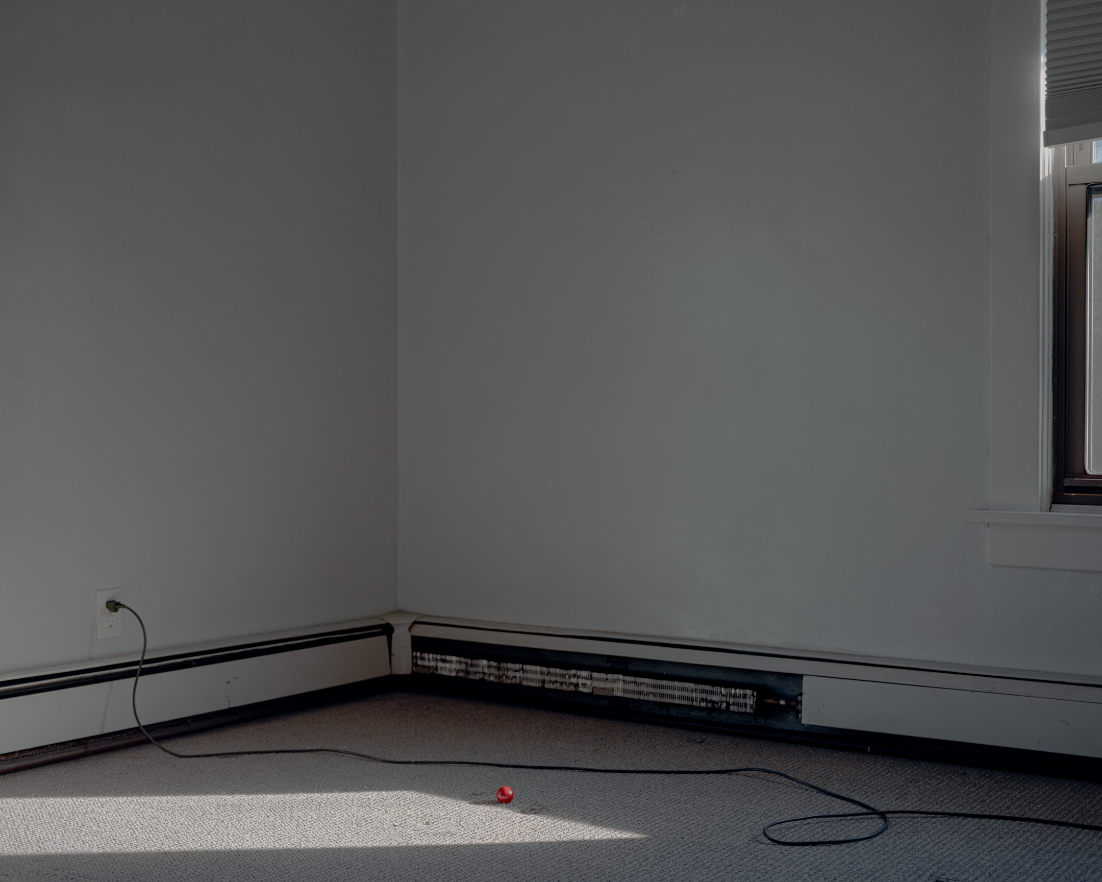 An empty room with a cord and a red ball on the floor