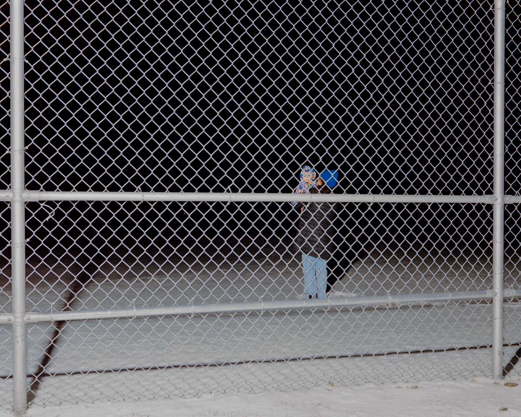 A tennis court seen through a chain-link fence